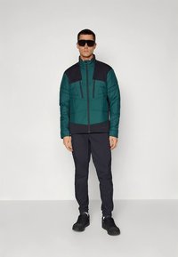 Pealmine jope türkiissinises ja tumesinis, lukuga ning kahe esitaskuga. Sobitatud mustade pükste ja mustade tossudega.