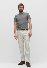 Grijze T-shirt met korte mouwen, gecombineerd met beige linnen broeken. De look wordt aangevuld met een bruine gevlochten riem en bruine schoenen.