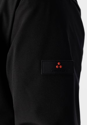 Pantaloni di tessuto nero caratterizzati da una texture liscia, con una toppa nera rettangolare e un logo con tre punti rossi sul lato.