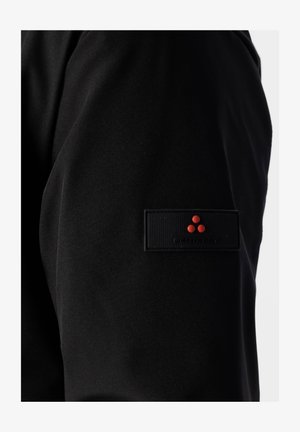 Pantaloni di tessuto nero caratterizzati da una texture liscia, con una toppa nera rettangolare e un logo con tre punti rossi sul lato.