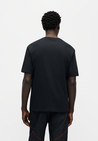 Μαύρο βαμβακερό μπλουζάκι με κανονικό λαιμόκοψη και κοντά μανίκια, με λεία υφή και άνετη εφαρμογή. Δεν διαθέτει ορατό λογότυπο ή σχέδια.