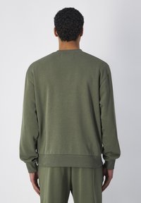 Felpa verde realizzata in morbido tessuto, con scollatura a girocollo, polsini e orlo ribattuti, e vestibilità rilassata. Nessun logo o decorazione visibile.