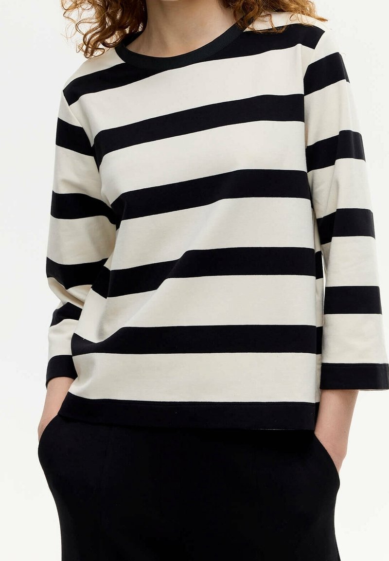 Top de manga larga a rayas negras y blancas con escote redondo y corte holgado; tela suave con rayas horizontales anchas.