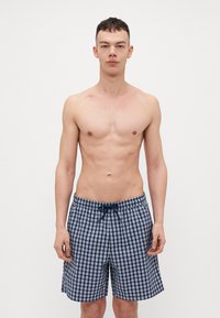 Marineblå rutete svømmedrakt med snøring i midjen, laget av lett stoff med en avslappet passform, som ender over kneet.