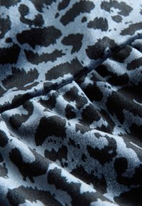 Melns un zils leoparda raksta audums ar maigu, zīdainu tekstūru; raksturo gludas, plūstošas formas uz tumšāka fona.