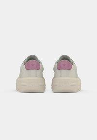 Pair of beige Converse All Star sneakers with thick soles and pink heel tabs, shown from the back on a white background.