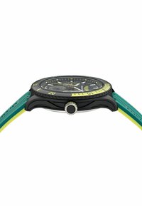Černé potápěčské hodinky s zeleným a žlutým silikonovým páskem. Mají texturovaný lunet, korunku z nerezové oceli a svítící hodinové značky.