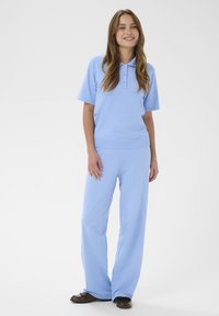 Ensemble deux pièces bleu clair comprenant un polo à manches courtes avec des boutons et un pantalon à jambes larges. Confectionné dans un tissu doux et texturé.