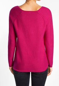 Suéter de punto en fucsia con un escote amplio, mangas raglán y un ajuste relajado. Presenta un tejido texturizado y un dobladillo ligeramente curvado.