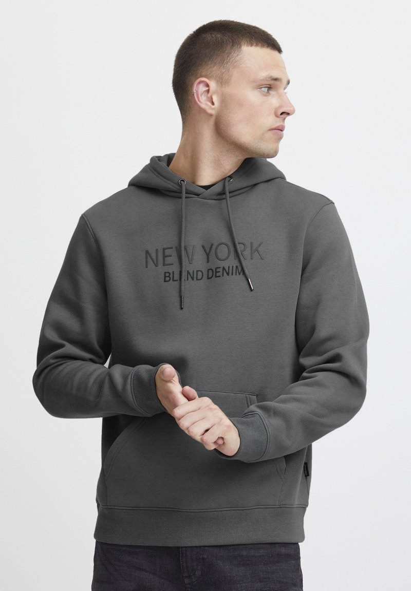 Gray hoodie with drawstrings, front kangaroo pocket, and black printed text "NEW YORK BLIND DENIM" on the chest. Soft, textured fabric.