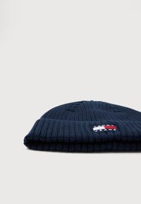 Ναυτικό μπλε ριγέ πλεκτό σκουφάκι με διπλωμένο μανίκι και ορθογώνια ετικέτα λογότυπου Tommy Jeans σε κόκκινο, λευκό και μπλε στο μπροστινό μέρος.