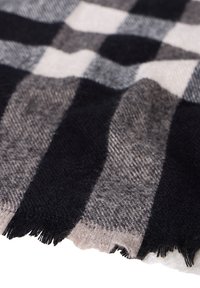 Bufanda a cuadros en negro, blanco y gris con una textura suave, bordes con flecos y un patrón tejido. Adecuada para diversos estilos y ocasiones.