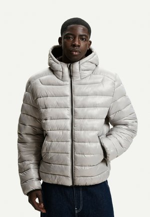 Ljusgrå pufferjacka med huva, med vertikala quiltade sektioner, full dragkedja fram och elastiska ärmslut. Slät, glänsande textur.