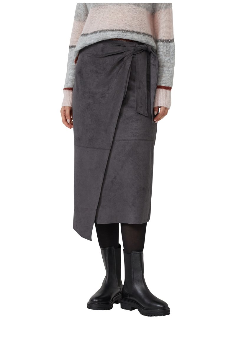 Grauer Wickelrock aus Wildleder mit Bindeschließe, glatter Textur und knielangem Design, kombiniert mit schwarzen Stiefeletten.