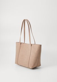 Beige tote bag aus Kunstleder mit zwei langen Handgriffen, flacher rechteckiger Form und sichtbaren Nähten. Glatte Textur, minimalistisches Design.
