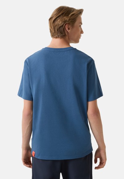 Modrá bavlněná tričko s kulatým výstřihem a krátkými rukávy. Obsahuje malou oranžovou cedulku na dolním lemu. Hladká textura, volný střih.