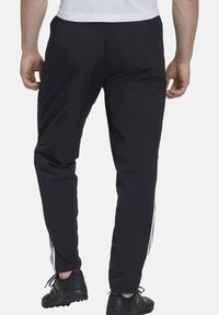 Schwarze Sporthosen aus leichtem Material, mit weißen Seitenstreifen, taillierter Passform und elastischem Bund.