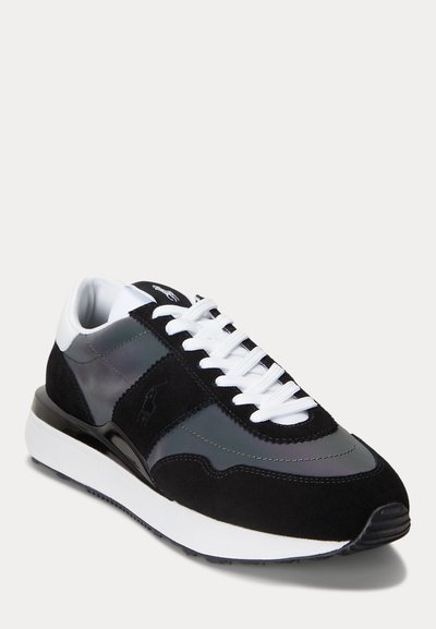 Schwarzer und grauer Sneaker mit niedrigem Schnitt, weißen Schnürsenkeln, dicker weißer Sohle und kleinem eingeprägtem Logo auf der Seitenblende.