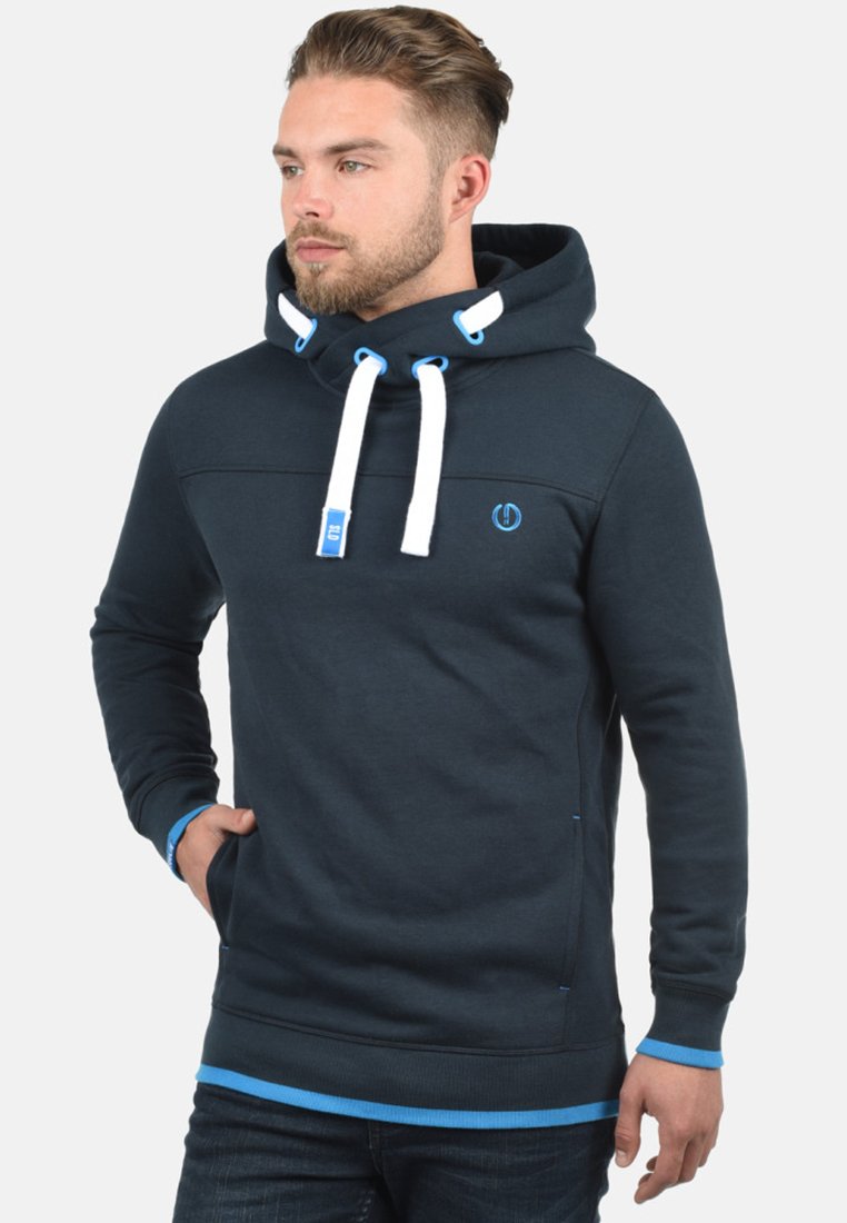 Donkerblauwe hoodie gemaakt van een katoenmix. Heeft een capuchon met trekkoord, blauwe accenten en een logo op de borst. Zachte textuur met een relaxte pasvorm.