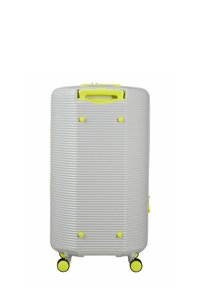 Valise rigide grise avec des rainures verticales, des accents jaunes, deux roues, une poignée supérieure et des pieds en plastique pour plus de stabilité.