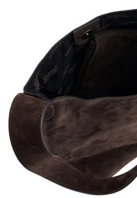 Brun ruskind håndtaske med en glat overflade, en blød tekstur og et mønstret indvendigt foer, hvor mærkenavnet "VENEZIA" er synligt.