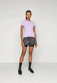 Fialové športové tričko s krátkym rukávom skombinované s čierno-sivými melírovanými šortkami. Logo Adidas na oboch kusoch oblečenia. Čierne športové ponožky a topánky.