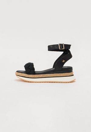 Fekete wedge szandál, csomózott kötél díszítéssel, állítható bokapánttal és textúrált parafa középtalppal. Kontrasztos fehér és gumi talp.