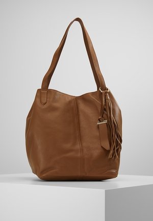 Brązowa skórzana torba na ramię z pojedynczym paskiem i detalem w postaci chwostów, prezentowana na białym postumencie na szarym tle.