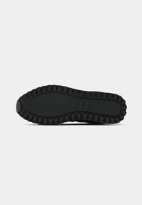 Suela de zapato de goma negra con patrón texturizado y bordes reforzados, que presenta surcos profundos para agarre y estabilidad. Logo grabado en el centro.