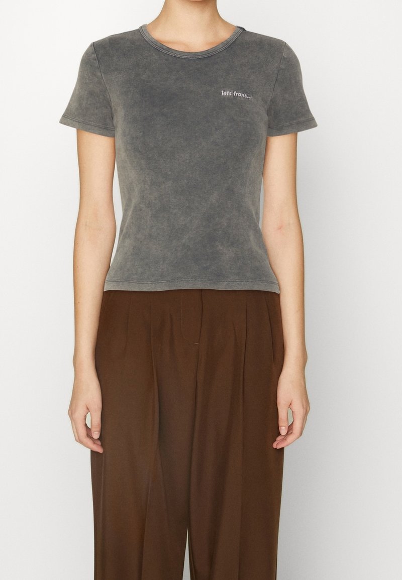 Szara bawełniana koszulka z okrągłym dekoltem i krótkimi rękawami. Posiada wyblakły wygląd oraz mały haftowany napis na górnej lewej stronie.