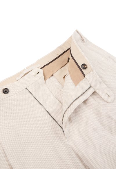 Pantalon beige clair avec un petit motif à carreaux, doté d'une fermeture éclair ouverte, d'une fermeture à bouton, et d'un détail de ceinture intérieure avec doublure beige.