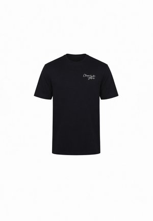 Musta lyhythihainen t-paita, jossa on pieni valkoinen käsinkirjoitettu logo vasemmassa rinnassa, jossa lukee "Cleargarden Studios."