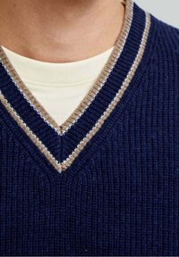 Granatowy sweter dzianinowy z dekoltem w serek, z beżowymi i białymi paskami wzdłuż kołnierza. Teksturowana tkanina i prążkowany wzór.