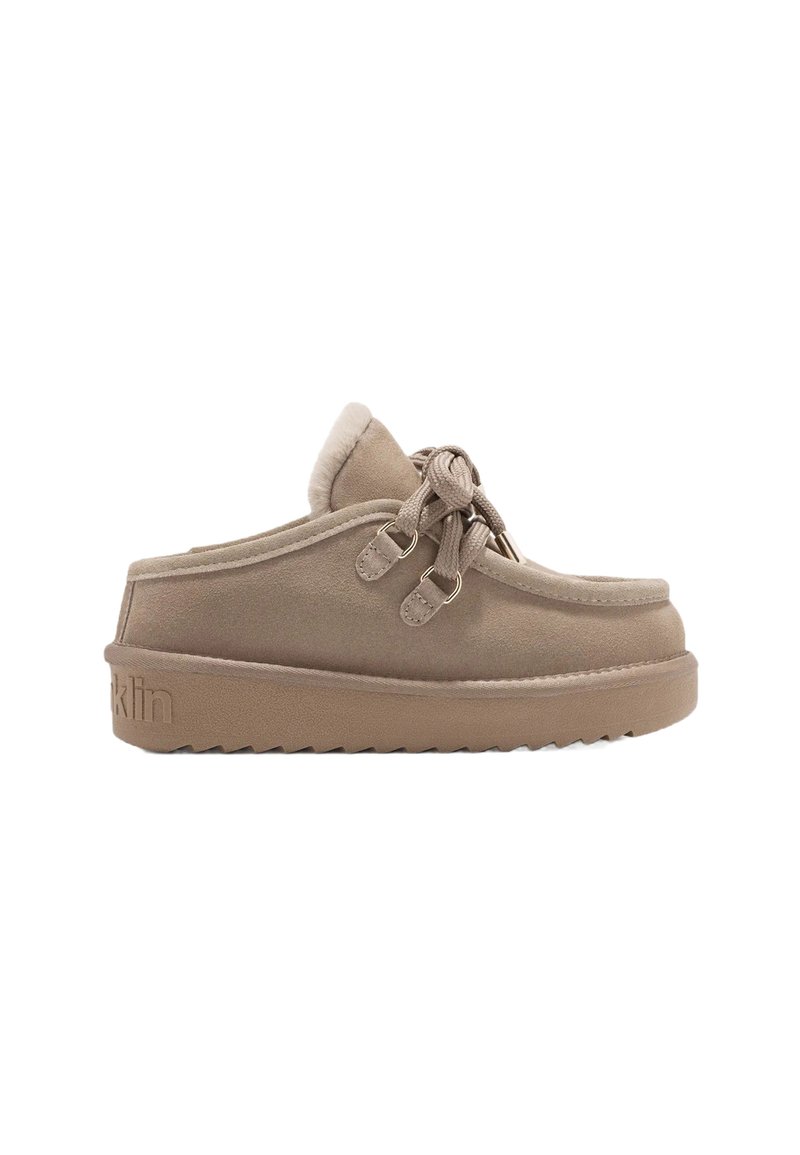 Chaussure beige à enfiler avec semelle épaisse, bout rond, doublure douce et lacets décoratifs noués en nœud sur le côté.