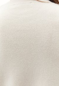 Maglione a coste color beige chiaro con una texture morbida, caratterizzato da un motivo sottile, un collo rotondo e un design aderente.