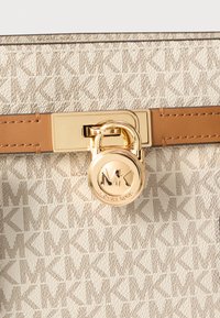 Borsa color cuoio e crema con motivo monogramma MK, tessuto testurizzato, ferrature dorate e dettaglio lucchetto con il logo del designer.