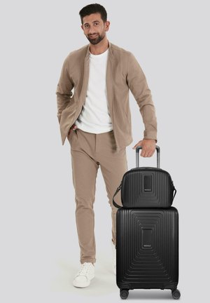 Conjunto de maletas rígidas negras con textura acanalada; incluye una maleta grande con ruedas y un pequeño bolso desmontable en la parte superior.