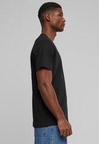 Sort crew-neck t-shirt lavet af bomuld, kortærmet, almindelig pasform, med en glat tekstur og et minimalistisk design.