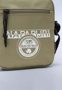 Borsa a spalla verde in tessuto con chiusura con zip, grande stampa con logo e design del globo e dell'Antartide, e tracolla regolabile.