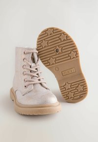 Stivaletti metallici rosa alla caviglia con design alla schiava, suole in gomma con motivi a stella e una superficie testurizzata per un ulteriore interesse visivo.