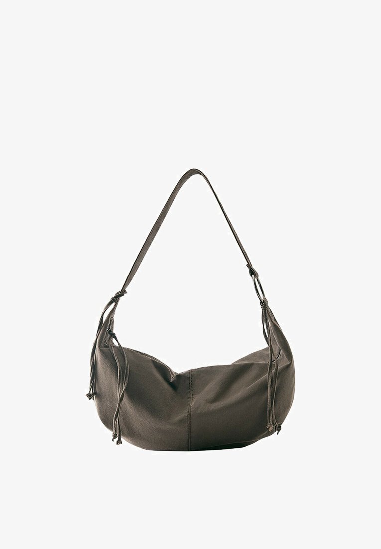 Sac à bandoulière en cuir marron foncé doux avec une seule sangle et des pompons décoratifs de chaque côté, présenté sur fond blanc.