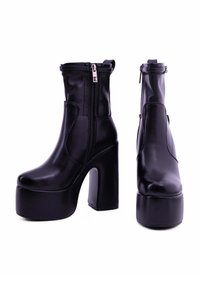 Stivali ankle in ecopelle nera con zeppa alta e cerniere laterali. Caratterizzati da una texture liscia e un design moderno e slanciato.