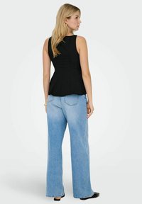 Zwarte peplumtop met een aansluitende bodice en brede bandjes, gecombineerd met lichtblauwe high-waisted wijde jeans. Soepele stof met minimale details.