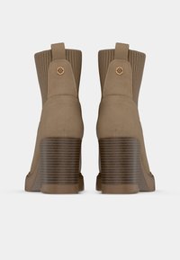 Botine bej cu gleznă, cu un prindere rișată, tocuri din lemn texturat și un material neted, asemănător cu suedeul, cu un accent circular.