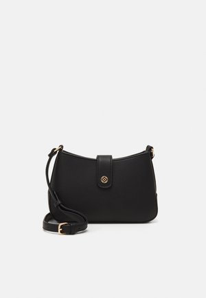 Sac bandoulière en cuir noir avec sangle ajustable, boucle dorée et emblème circulaire doré sur le rabat avant.