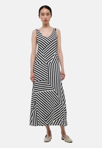 Robe maximale en noir et blanc, avec un motif géométrique à rayures. Fabriquée en tissu lisse avec un corsage ajusté et une jupe fluide.