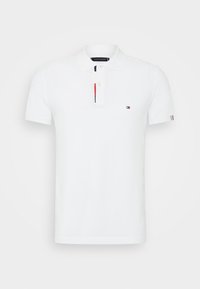 Polo blanc en coton, présentant une patte de boutonnage à deux boutons avec des accents rouge et marine, et un petit logo sur la poitrine gauche. Manches courtes.