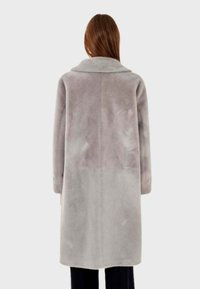Cappotto in pelliccia artificiale di grigio chiaro con colletto a intaglio, maniche lunghe e design di lunghezza intermedia. Texture morbida con una leggera variazione di colore.