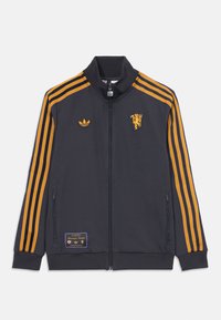 Mörkgrå zip-up jacka med gulorange ränder, ribbad krage och mudd. Har broderade logotyper och en tygpatch på den nedre framsidan.