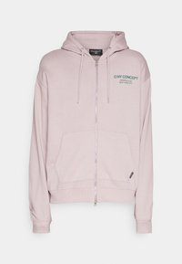 Sudadera con capucha de color rosa claro con cremallera frontal, capucha con cordón y un bolsillo delantero. Logotipo de la marca impreso en el lado izquierdo del pecho en color verde azulado. Tejido suave.